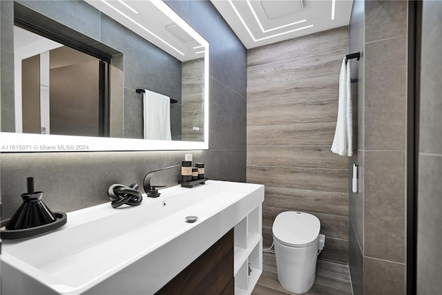 bathroom with toilet, vanity, tile walls, and wood-type flooring