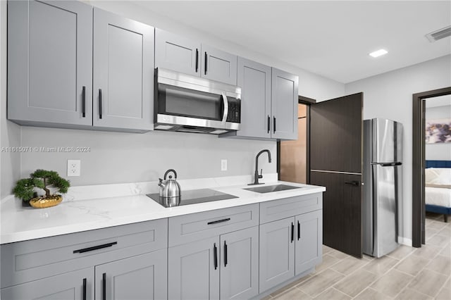 kitchen featuring light hardwood / wood-style floors, stainless steel appliances, sink, and gray cabinetry