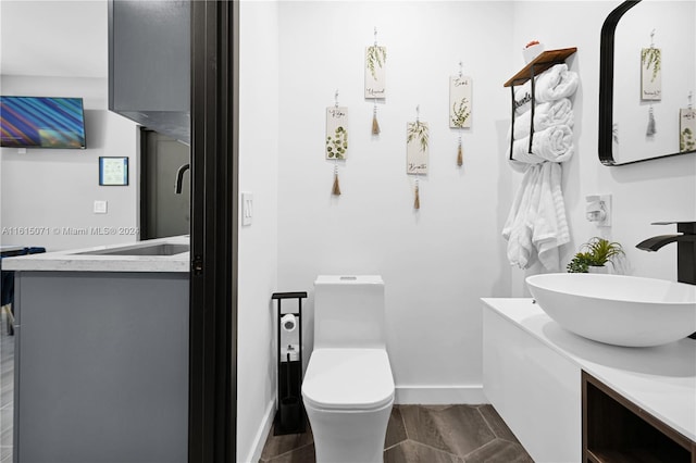 bathroom with toilet, vanity, and hardwood / wood-style floors