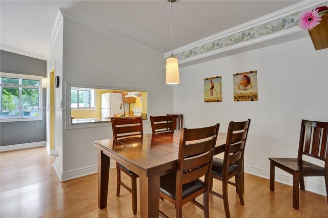 dining space with ornamental molding and light wood-type flooring