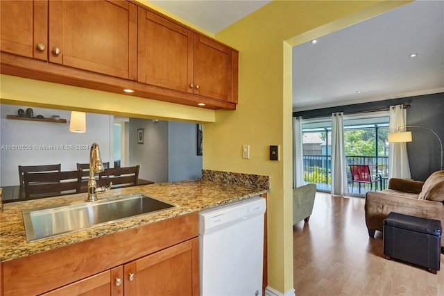 kitchen with light stone countertops, light wood-type flooring, white dishwasher, a sink, and open floor plan