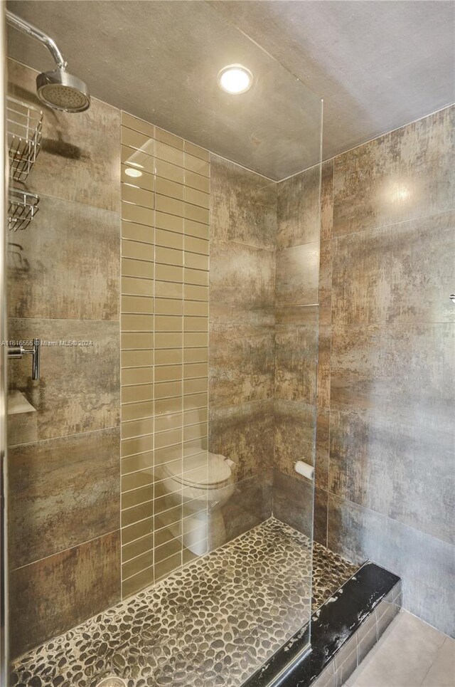 bathroom with a shower with door and toilet