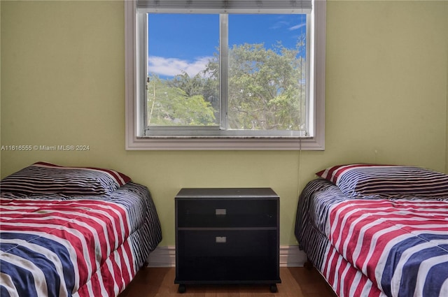 bedroom with multiple windows and dark wood-type flooring