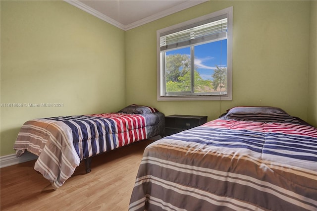 bedroom with crown molding, wood finished floors, and baseboards