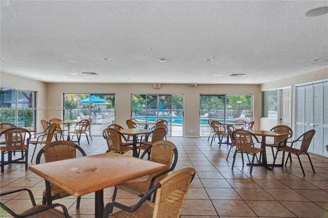 dining space with light tile patterned flooring, a textured ceiling, and a wealth of natural light