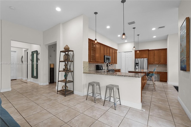 kitchen featuring kitchen peninsula, a kitchen breakfast bar, backsplash, and stainless steel appliances