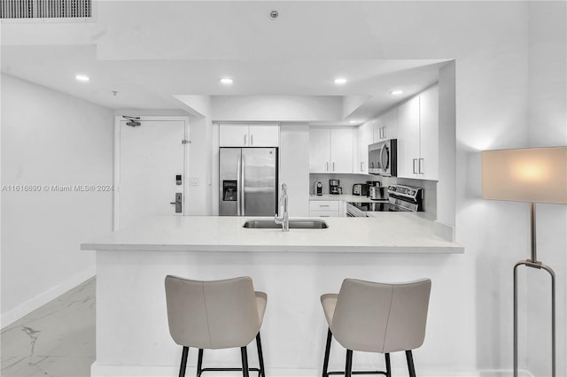 kitchen featuring stainless steel appliances, sink, light tile patterned flooring, white cabinetry, and kitchen peninsula