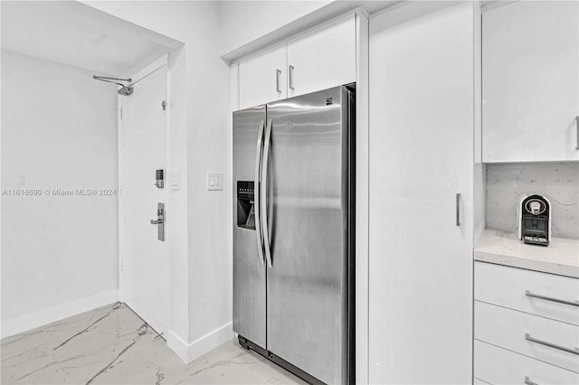 kitchen featuring decorative backsplash, white cabinetry, stainless steel fridge with ice dispenser, light stone countertops, and light tile patterned floors