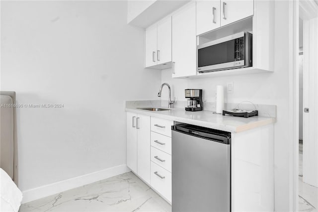 kitchen with sink, stainless steel appliances, white cabinetry, and light tile patterned floors