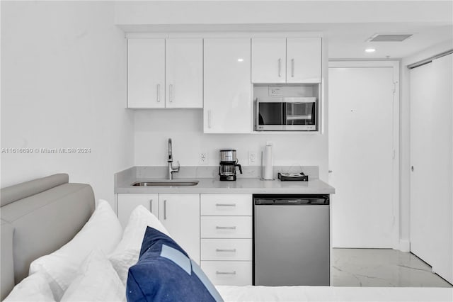 kitchen featuring appliances with stainless steel finishes, sink, light tile patterned floors, and white cabinets