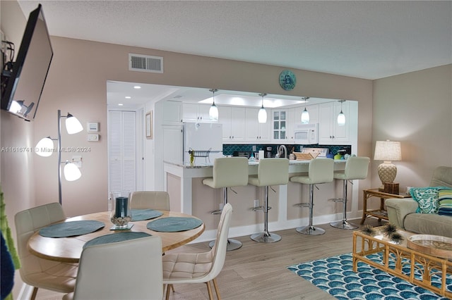 dining area with light hardwood / wood-style flooring and a textured ceiling