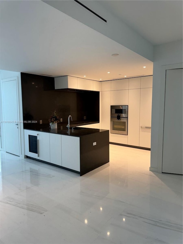 kitchen with stainless steel double oven, sink, and white cabinets