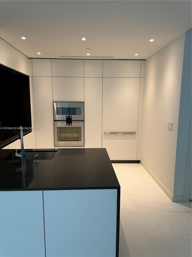 kitchen with sink, white cabinets, and double oven