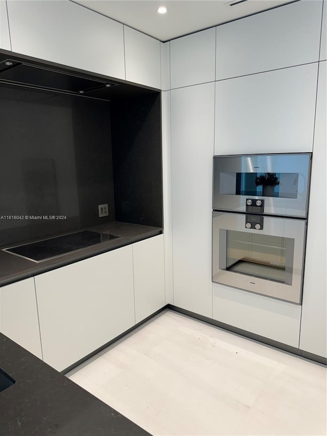 kitchen with white cabinetry, black electric cooktop, light hardwood / wood-style flooring, and double oven