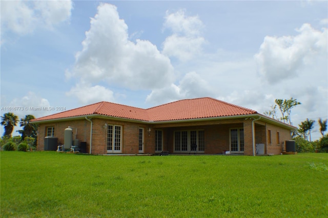 rear view of property with central AC and a lawn