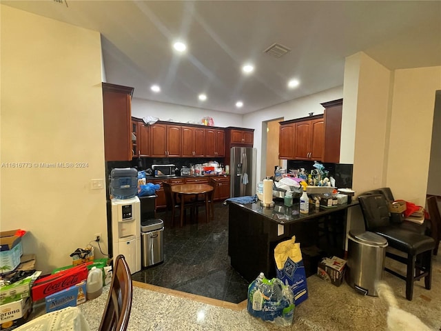 kitchen featuring stainless steel fridge, dark tile patterned floors, and kitchen peninsula