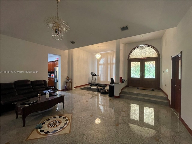 tiled entrance foyer featuring a high ceiling, french doors, and an inviting chandelier