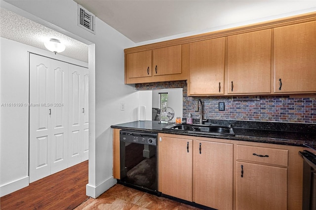 kitchen with dishwasher, sink, backsplash, dark stone counters, and a textured ceiling