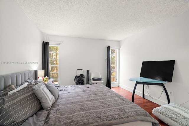 bedroom with a textured ceiling, hardwood / wood-style flooring, and multiple windows