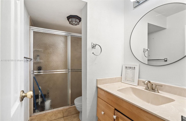 bathroom featuring toilet, vanity, tile patterned floors, and a shower with shower door