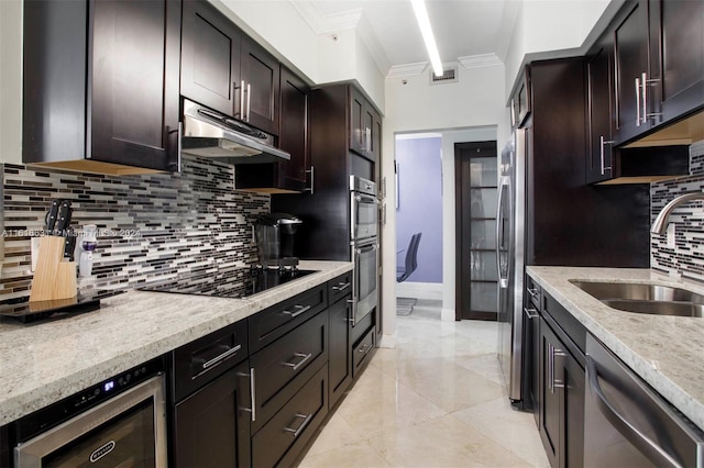 kitchen featuring tasteful backsplash, light stone counters, dark brown cabinets, stainless steel appliances, and sink