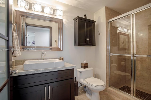 bathroom featuring tile patterned floors, vanity, toilet, and a shower with door