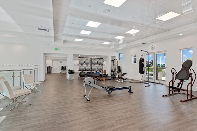 workout area with a paneled ceiling and light hardwood / wood-style flooring