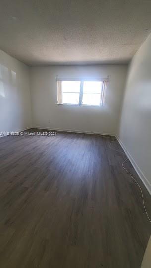 unfurnished room featuring dark hardwood / wood-style floors and a textured ceiling