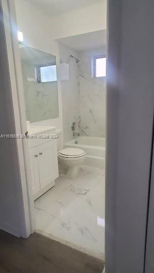 full bathroom with tiled shower / bath, vanity, and toilet