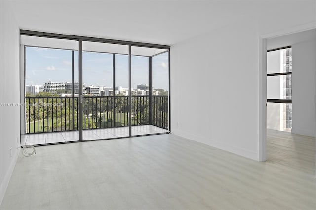 spare room featuring a wall of windows and light hardwood / wood-style flooring