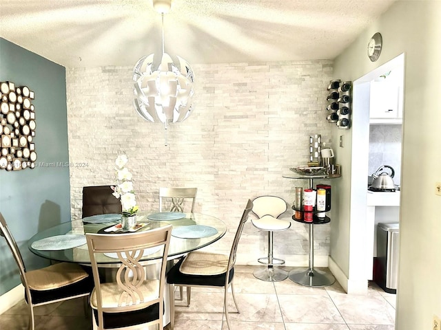 tiled dining room with an inviting chandelier and a textured ceiling