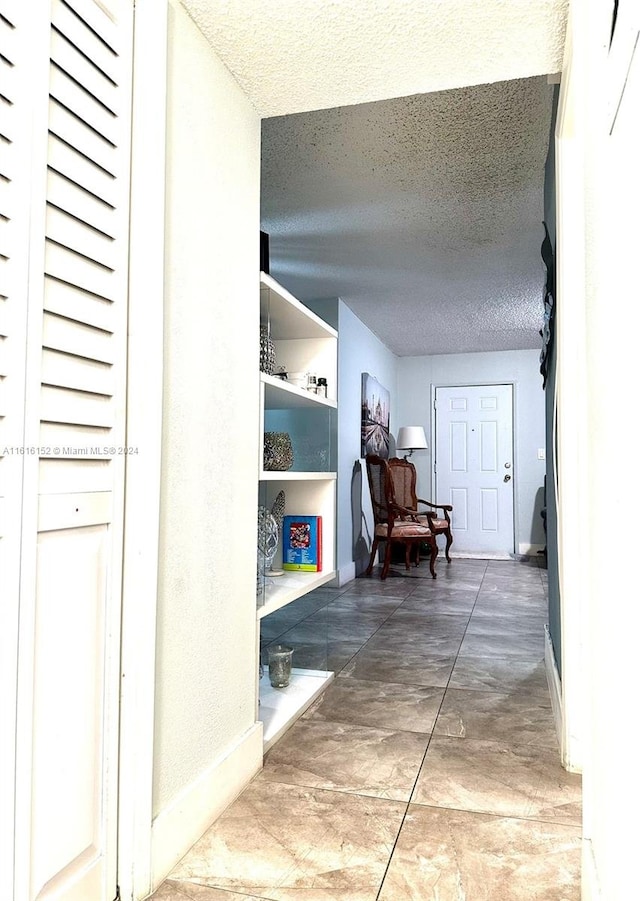 hallway with tile patterned flooring and a textured ceiling