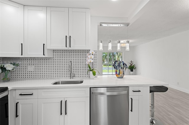 kitchen with sink, tasteful backsplash, stainless steel dishwasher, kitchen peninsula, and white cabinets