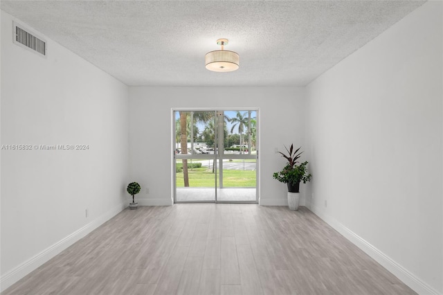 unfurnished room with light hardwood / wood-style floors and a textured ceiling