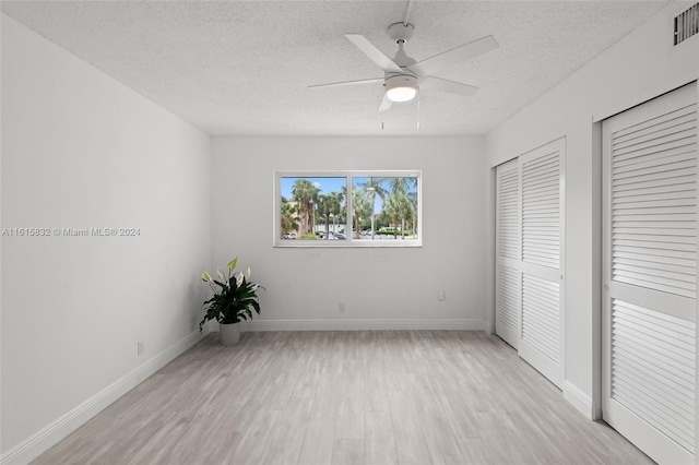 unfurnished bedroom featuring ceiling fan, a closet, a textured ceiling, and light wood-type flooring