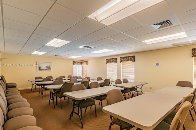 carpeted dining area featuring a paneled ceiling