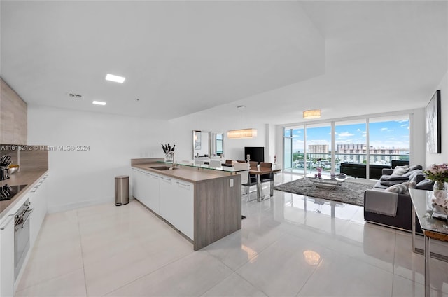 kitchen with white cabinetry, sink, black electric cooktop, and expansive windows