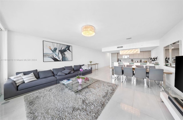 living room with light tile patterned flooring and a notable chandelier