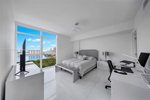 bedroom with light tile patterned floors, floor to ceiling windows, and a water view