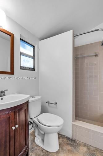 bathroom featuring vanity, a tile shower, and toilet