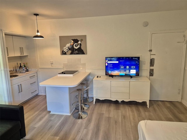 interior space featuring pendant lighting, light hardwood / wood-style flooring, and white cabinets