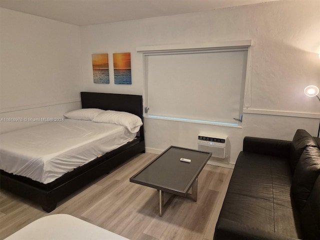 bedroom with light hardwood / wood-style floors and a wall mounted air conditioner