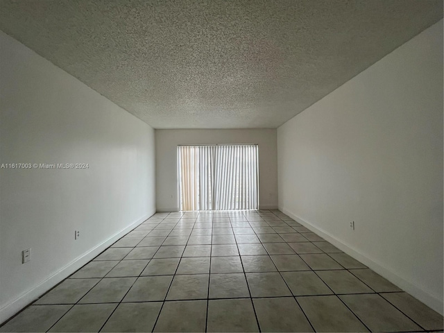 empty room featuring a textured ceiling and light tile patterned floors