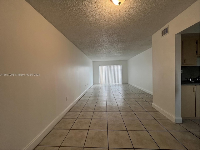 tiled empty room featuring a textured ceiling