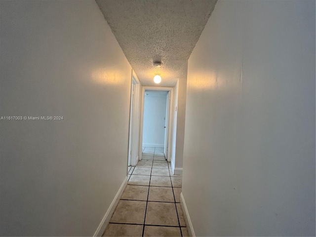 hall featuring a textured ceiling and light tile patterned floors