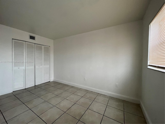 unfurnished bedroom featuring light tile patterned flooring and a closet