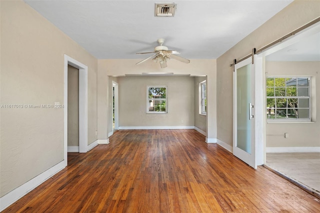 empty room featuring a healthy amount of sunlight, a barn door, and dark wood-type flooring