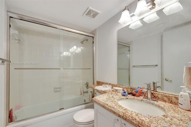 full bathroom featuring toilet, vanity, and shower / bath combination with glass door