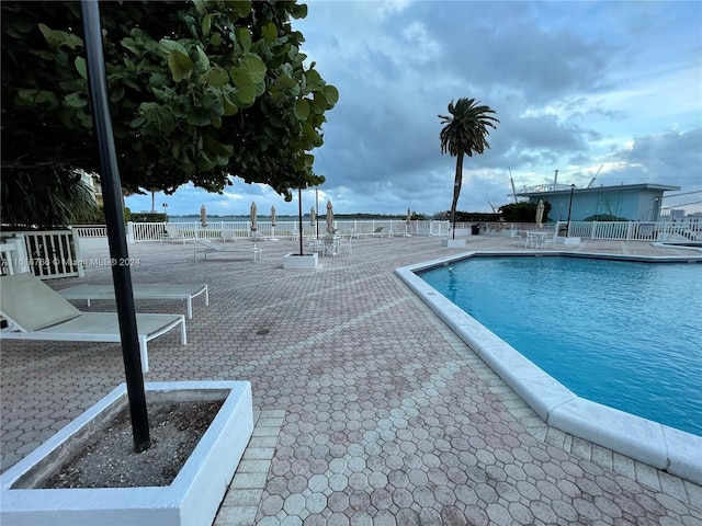 view of swimming pool with a water view and a patio