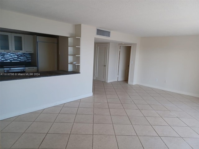 unfurnished living room with light tile patterned floors and a textured ceiling